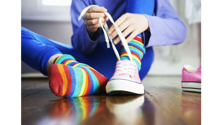 young child tying shoe laces with colourful socks