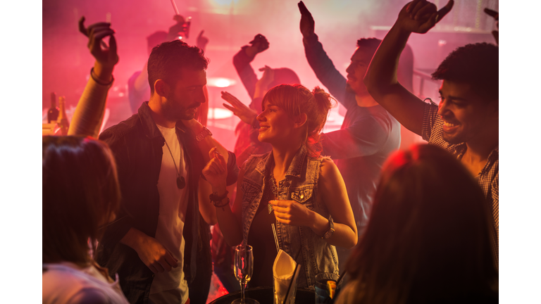 Young couple flirting during the night out at disco club.