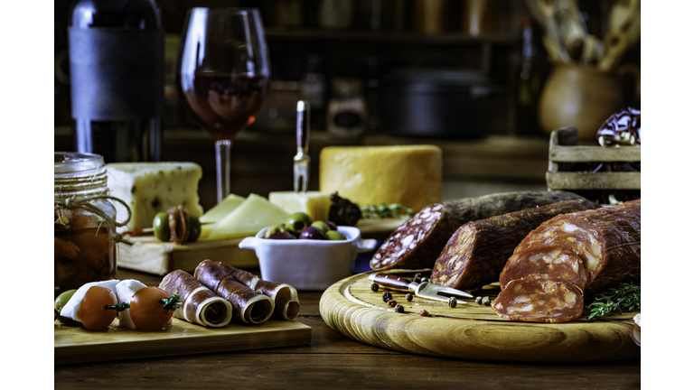 Tapas of cheese, cured ham, salami wine and chorizo on a rustic wooden table
