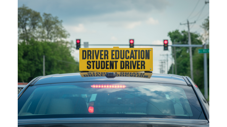 Student driver sign on top of car at stoplight