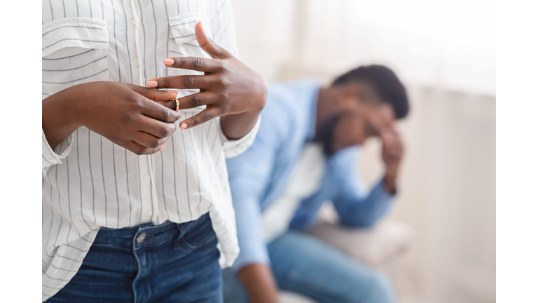 Unrecognizable black woman removing wedding ring from finger, divorcing with husband
