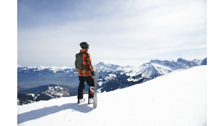 Snowboarder looking across mountain range.