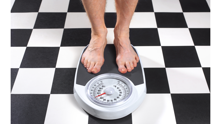 Overweight Man Standing on Bathroom Scales