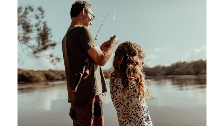 Dad fixes fishing rod for his daughter