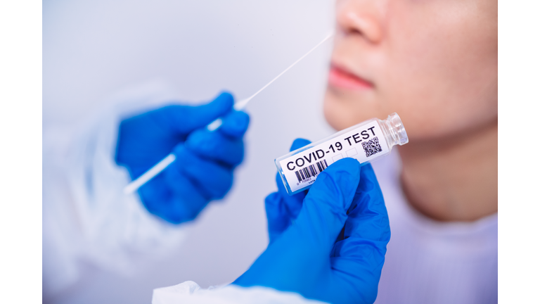 Doctor in protective gloves & workwear holding Testing Kit for the coronavirus test