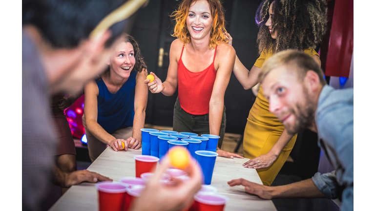 Young friends playing beer pong at youth hostel - Free time travel concept with backpackers having unplugged fun at guesthouse - Happy people on playful genuine attitude - Vivid vignetting filter