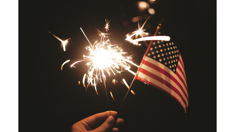 Hand holding lit sparkler with American Flag