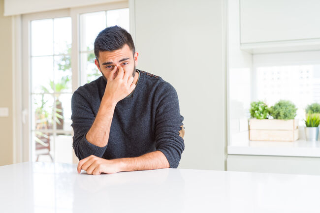 Handsome hispanic man wearing casual sweater at home tired rubbing nose and eyes feeling fatigue and headache. Stress and frustration concept.