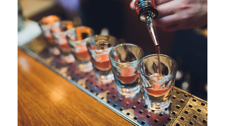 Bartender man making hot alcohol shots on the bar in the pub with a professional burner. The bartender lights a lighter over a glass.Relax in the nightclub. Hot fire drinks. Lets the party.