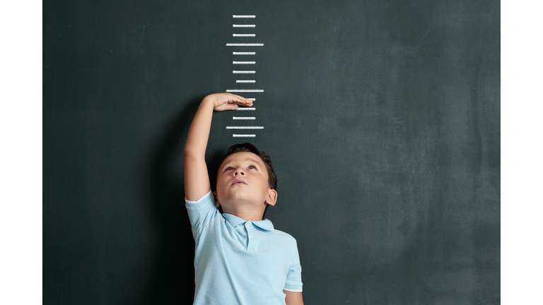 Child measuring his height on wall. He is growing up so fast.