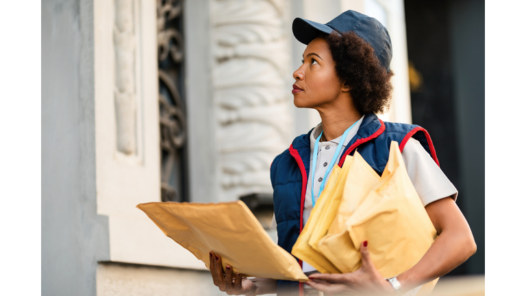 African American postal worker delivering mail in the city.