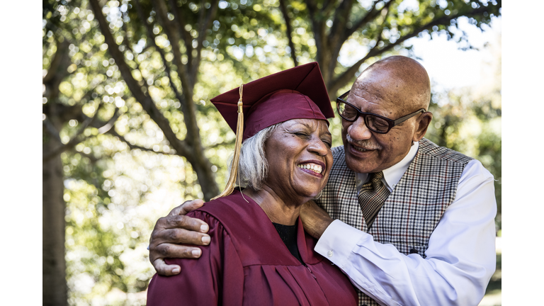 Senior woman in college graduation gown with husband
