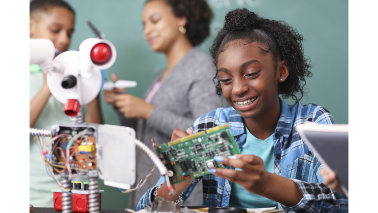 Junior high school age school students build robot in technology, engineering class.