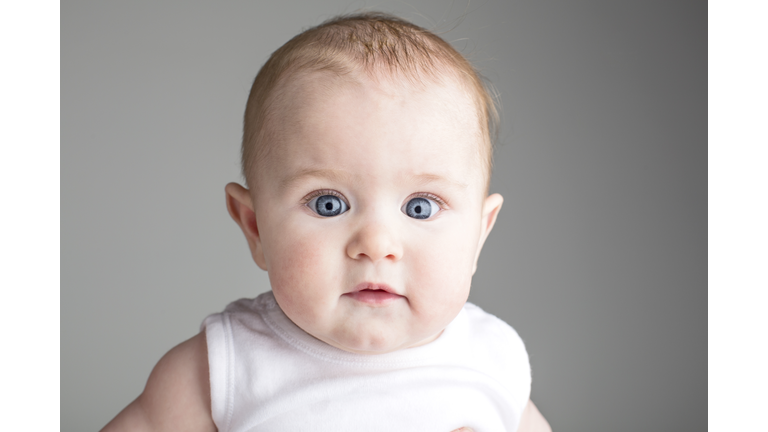Blue eyed baby girl looking to camera, studio