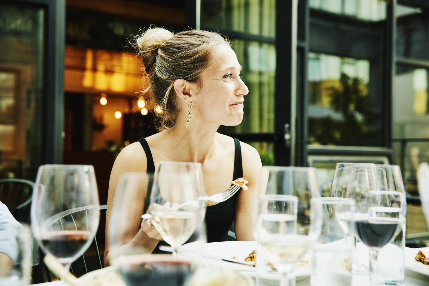 Smiling woman sharing dinner with friends on restaurant patio on summer evening