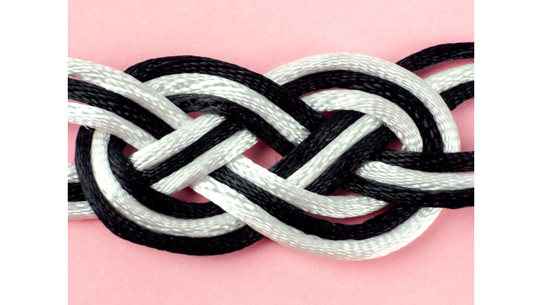 A string bracelet with sailor knots on a pink background