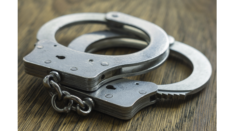 Handcuffs. A pair of handcuffs photographed on a wooden background.