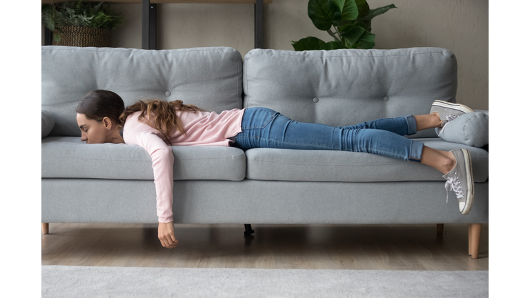 Young woman lying buried her face in sofa feels tired