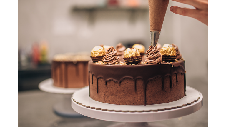 Confectioner decorating chocolate cake, close-up.