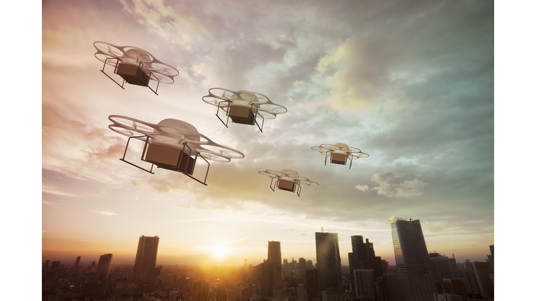 Five delivery drones flying above the city at sunset