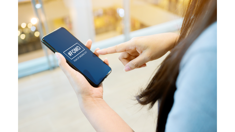 FOMO, fear of missing out concept. Close-up image of woman hand using mobile smartphone