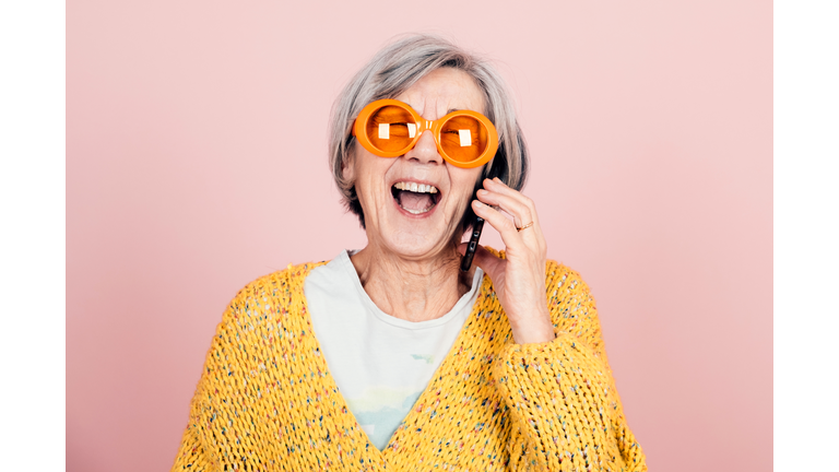 Happy Young Style Elderly Grandma With Orange Sunglasses And Modern Looking Laughing On The Phone