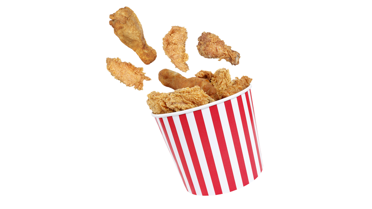 Perfect fried chicken pieces flying around in red white striped box