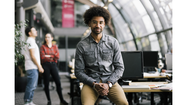 Portrait Of Office Employee Leaning On Desk