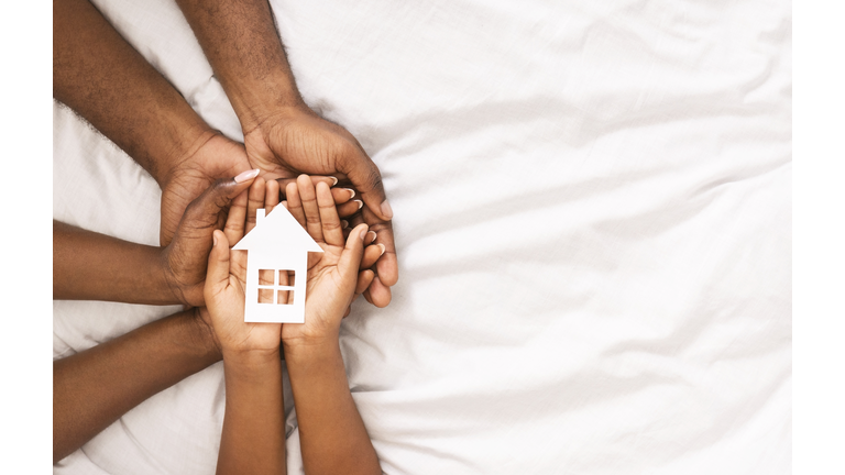 Closeup of paper house in hands of african american family