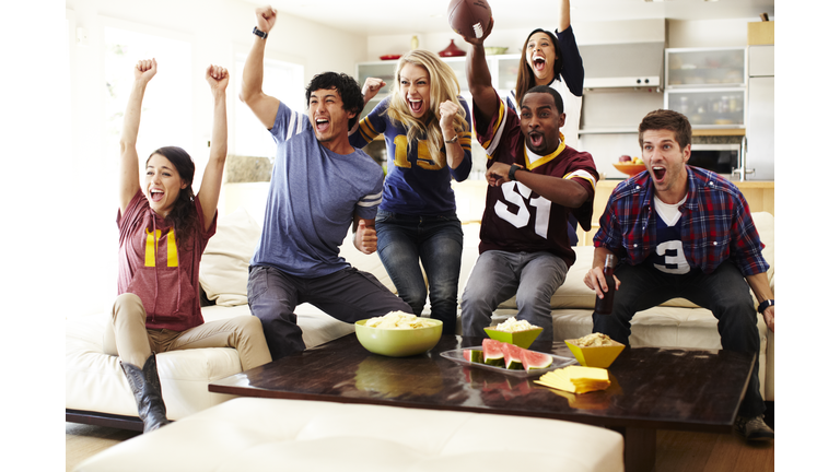 Friends watching football in living room.