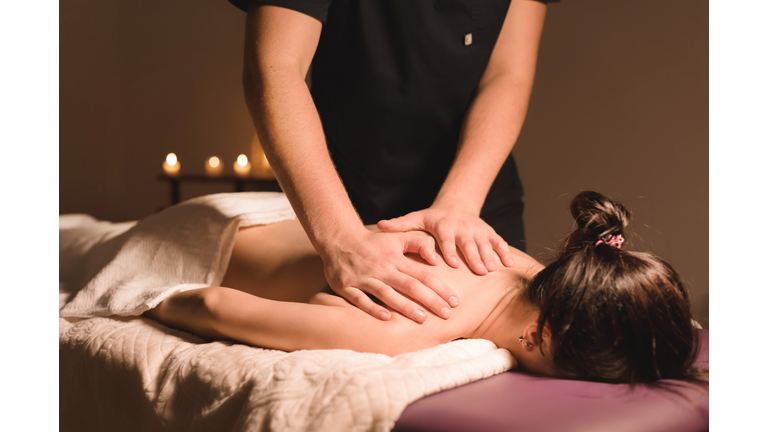 Close up Male manual worker doing spa massage to a young girl in a dark room