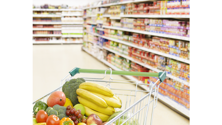 Shopping cart in grocery store full of fruits and vegetables