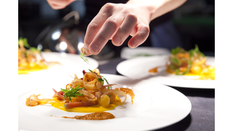 Hand garnishing a plate of poached lobster with carrot crue-cuite