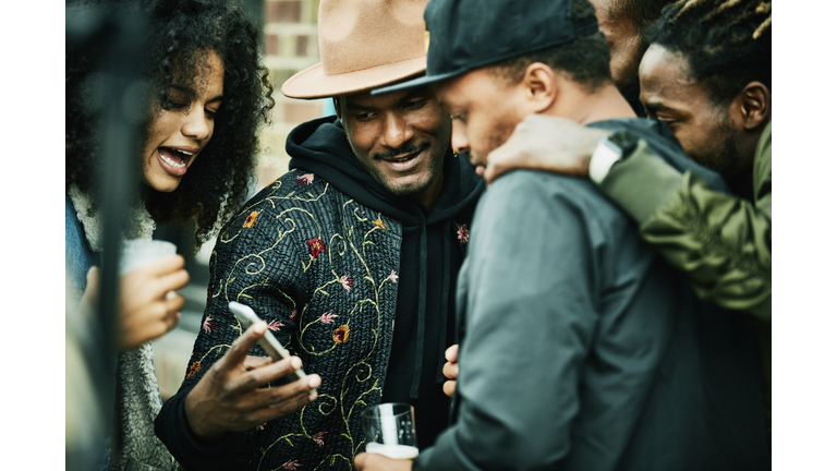 Friends looking at smart phone during party at outdoor restaurant