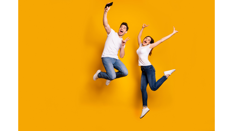 Full length side profile body size photo funky funny crazy people she her he him his guy lady jump high show v-sign make take selfies wear casual jeans denim white t-shirts isolated yellow background