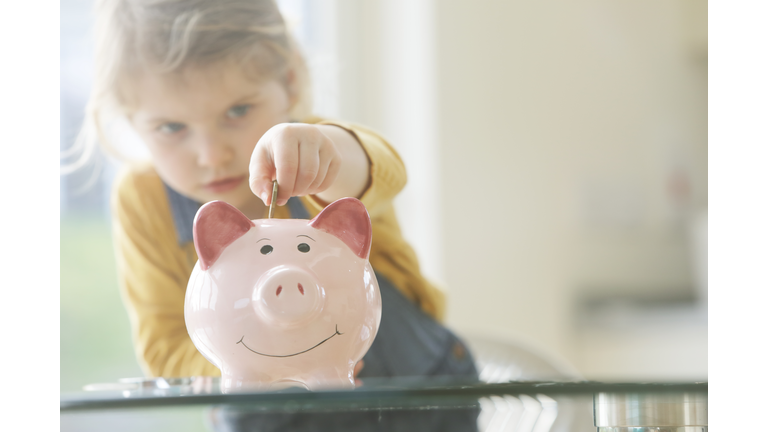 Young child putting coins into piggy bank