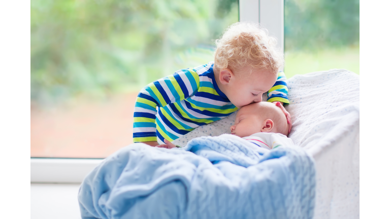 Little boy kissing newborn baby brother