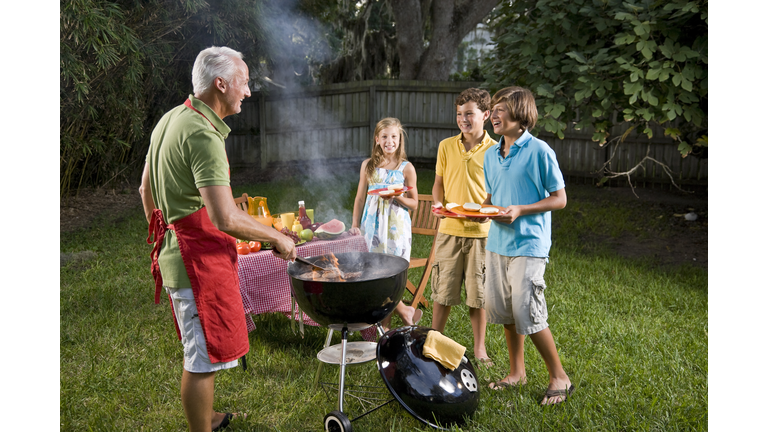 Family grilling burgers on backyard barbecue grill