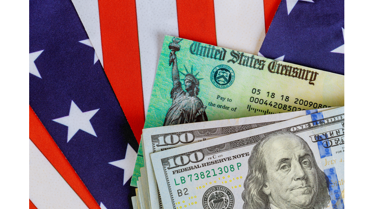 Stimulus economic tax return check and US 100 dollar bills currency with US flag