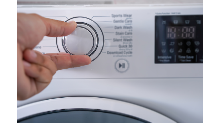 Cropped Hand Of Person Adjusting Washing Machine Knob