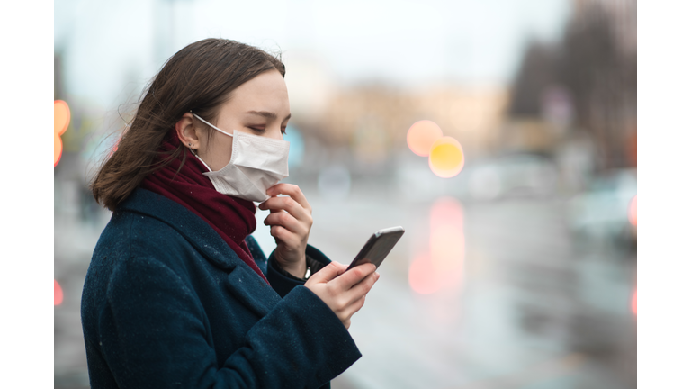 Young girl wearing a protective face mask and checking air pollution with smartphone