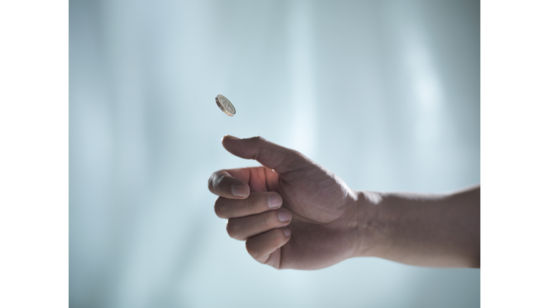 Man flipping one pound coin, pounds sterling