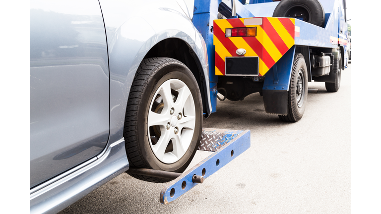 Tow truck towing a broken down car on the street