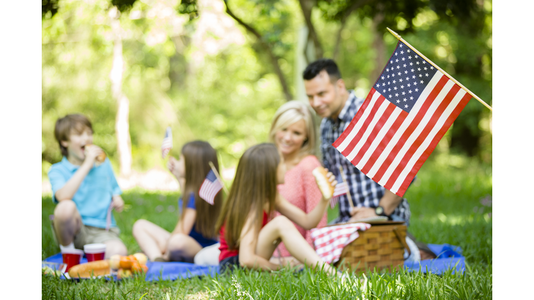 Family enjoys July 4th picnic in summer season. American flag.