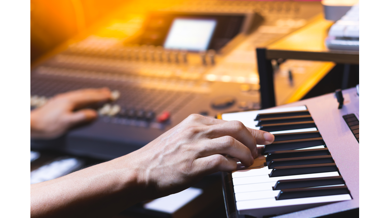 composer, producer hands playing keyboard for recording midi track in home studio. music production concept