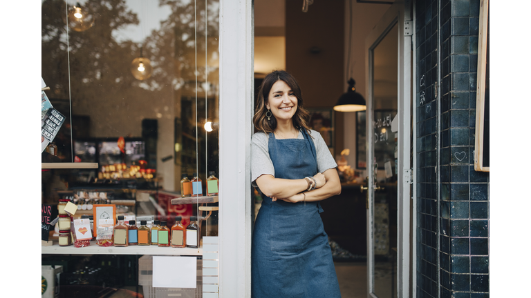 Portrait of confident female owner standing at entrance of deli