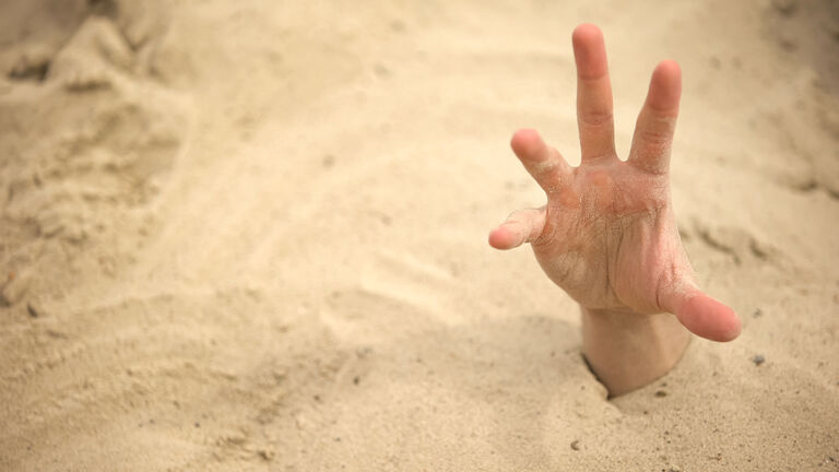 Hand sinking in quicksand, trying to get out, tips to survive in desert, buried