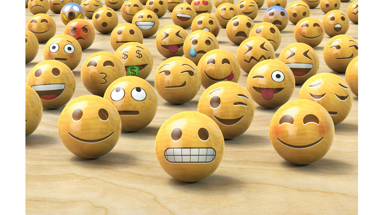 Many wooden emoticon or Emoji face balls, one up front