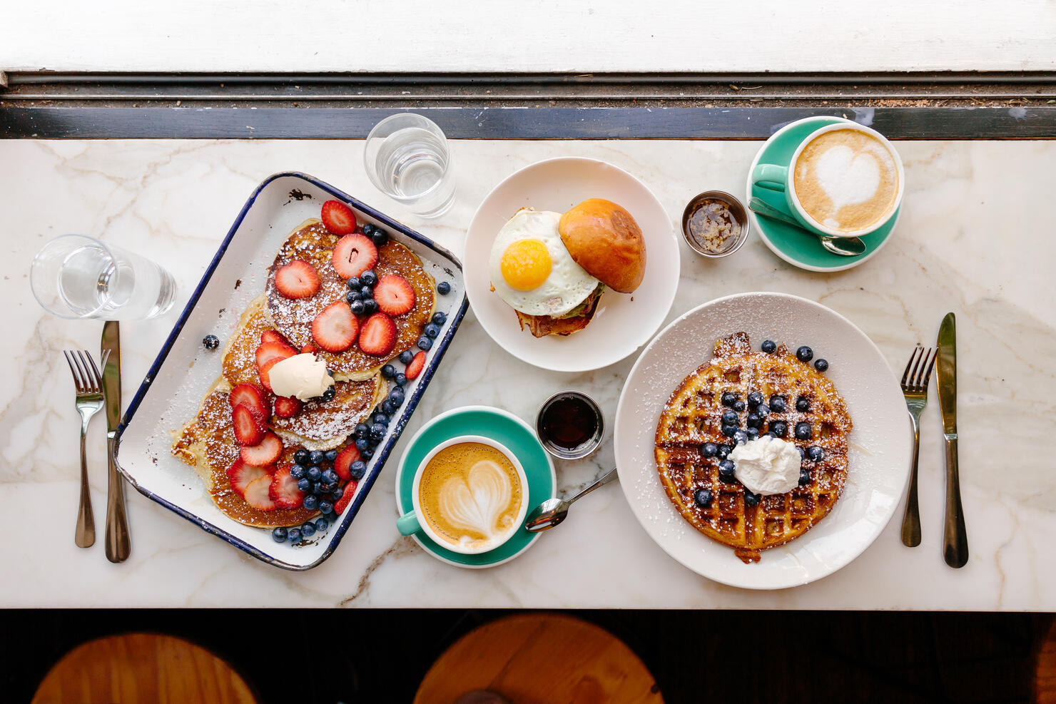 Directly above view of a brunch with pancakes, waffle and burger with fried egg in a restaurant