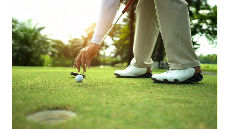 Hand putting golf ball on tee in golf course